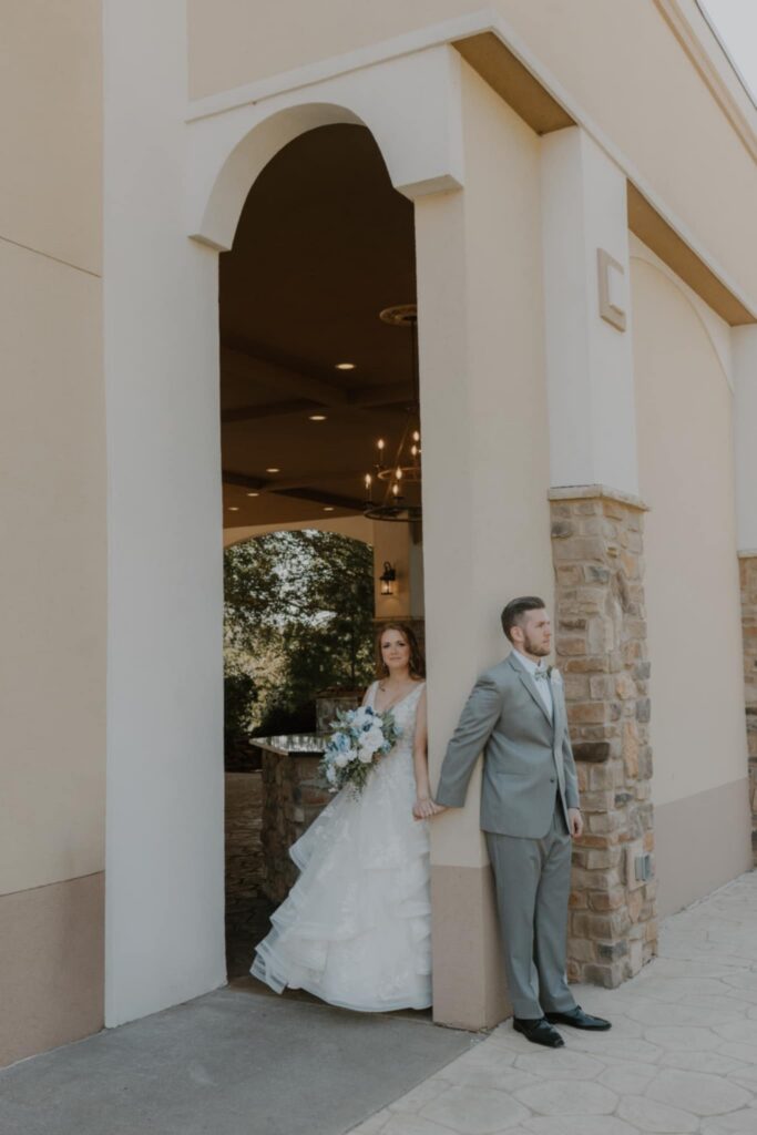Bride and groom first touch. tall building, brick and stone, archways, first look, wedding day