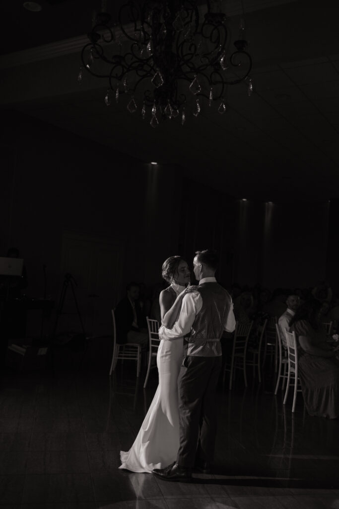 timeless black and white wedding photo, first dance, chandelier, gorgeous and elegant venue for reception with dimmable lighting and natural light