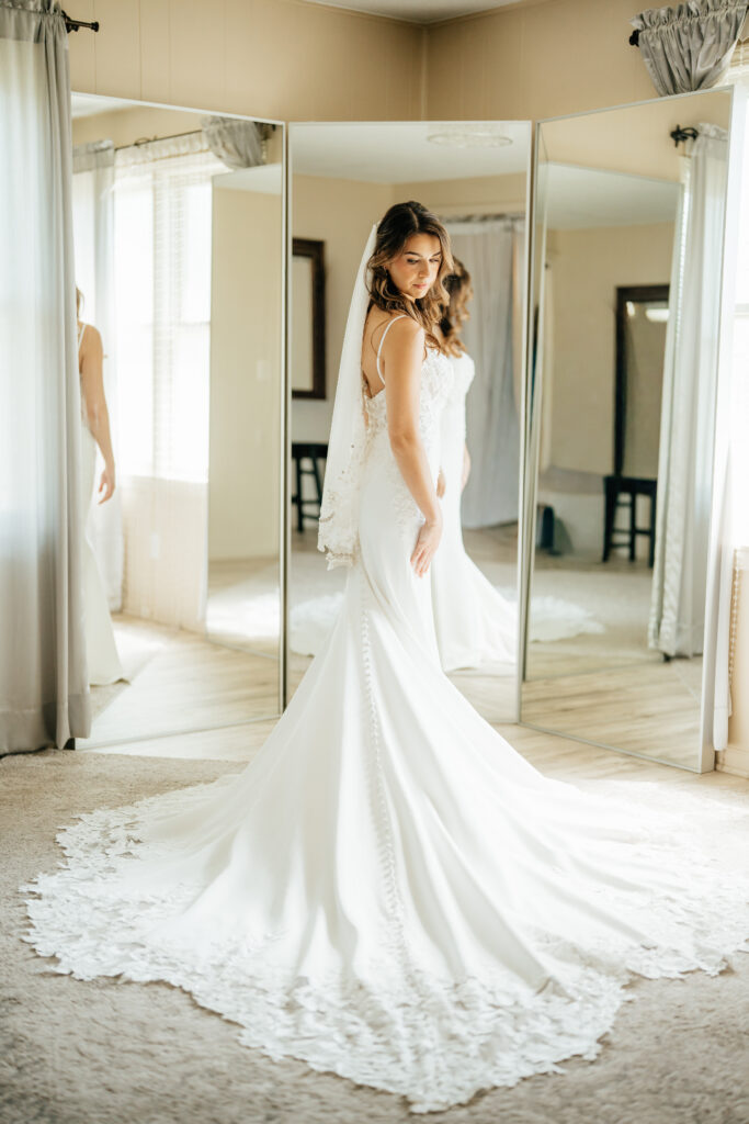 bride in wedding dress with large mirrors and veil in wedding venue cottage, bridal suite