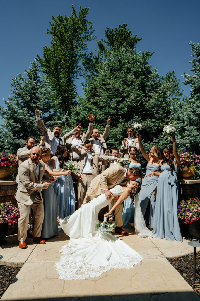 bridal party wedding photography, outdoor bride and groom dip, first kiss, bridesmaids, groomsmen, celebrating